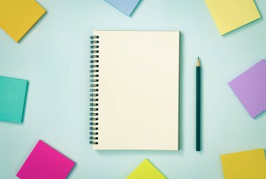Spiral Notebook ya da Spring Notebook in Unline Type and Multi Color Sticky Note and kalem on Blue Pastel Minimalist Arkaplan. Vintage Tondaki Orta Çerçevede Spiral Not Defteri Model