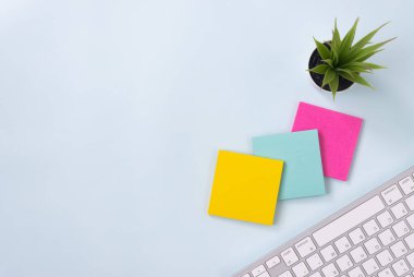 Modern Temiz Yaratıcı Ofis Masasında 3 Yapışkan Not ve Ofis Bitkisi ve Bilgisayar Klavyesi veya Üst Görünüm veya Düz Yatakta Ofis Masası. Mavi Çalışma Alanı Minimalist Arkaplan ve Ofis Malzemeleri