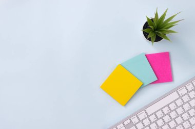 Modern Temiz Yaratıcı Ofis Masasında 3 Yapışkan Not ve Ofis Bitkisi ve Bilgisayar Klavyesi veya Üst Görünüm veya Düz Yatakta Ofis Masası. Mavi Çalışma Alanı Minimalist Arkaplan ve Ofis Malzemeleri