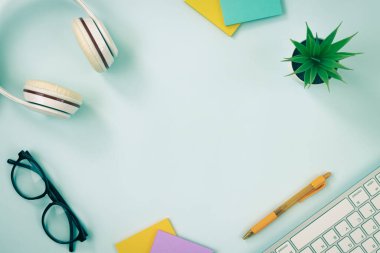 Modern Temiz Yaratıcı Ofis Masası veya Masa Üst Görünüm Masası veya Düz Yat ve Kırtasiye Klavye, Kulaklık, Kalem, Yapışkan Not, Ofis Bitkileri, Gözlükler. Vintage Tone Çalışma Alanı Minimalist Arkaplanı