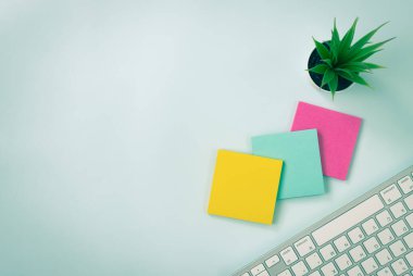 Modern Yaratıcı Ofis Masasında 3 Yapışkan Not ve Ofis Bitkisi ve Bilgisayar Klavyesi veya Üst Görünüm veya Düz Yerde Ofis Masası. Mavi Çalışma Alanı Minimalist Arkaplan ve Klasik Ton Ofis Malzemeleri
