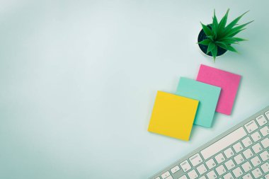 Modern Temiz Ofis Masasında 3 Yapışkan Not ve Ofis Bitkisi ve Bilgisayar Klavyesi Ya da Üst Görünüm veya Düz Yerde Ofis Masası. Mavi Çalışma Alanı Minimalist Arkaplan ve Klasik Ton Ofis Malzemeleri