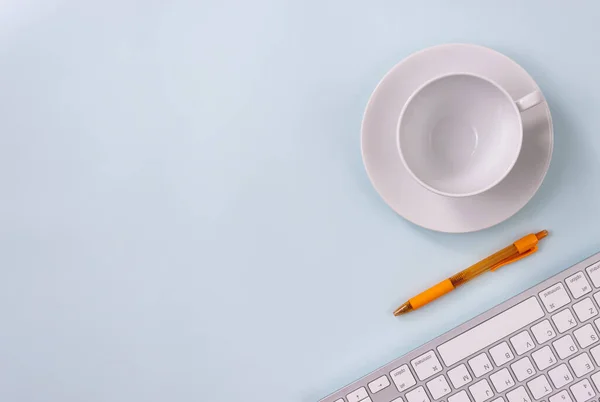 Coffee Cup and Pen and Computer Keyboard on Modern Clean Creative Office Desk or Office Table on Top View or Flat Lay. Blue Workspace Minimalist Background and Office Supplies