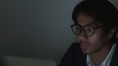 Kamyon Asyalı Sigorta Ajanı Takım Elbiseli İşadamı Gözlüklü Dizüstü bilgisayar takıyor ve Zoom View 'daki ofiste geç saatlere kadar çalışıyor