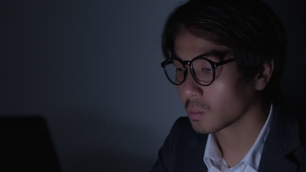 アジアの保険代理店のビジネスマンがスーツを着て眼鏡をタイプし ズームサイドビューでオフィスで遅く働く — ストック動画