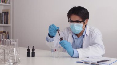 Korona Virüs Hastalığı Laboratuvarında Asyalı Doktor veya Bilim Adamı Yüzü Maske ve Beyaz Önlük Giyin veya Önlük Test Çözümü
