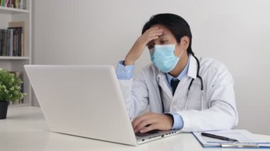 Laboratuvar önlüklü ya da steteskop maskeli genç Asyalı Doktor 19. Karakol 'da ya da Corona Virüs Durumu' nda çalışırken maske takıyor.