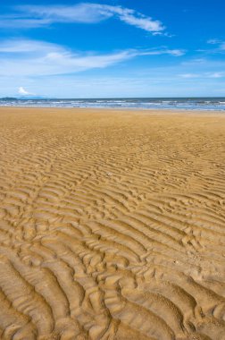 Güzel mavi gökyüzünün altındaki alçak gelgit sırasında deniz kumsalı deseni gibi ölçeklendir.
