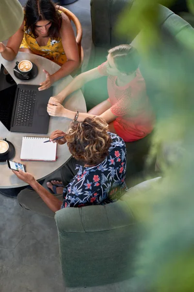 Foto di stile di vita candido di tre diversi colleghi millenari che pianificano un caffè con computer portatile in un luminoso caffè che serve caffè equo e solidale — Foto Stock