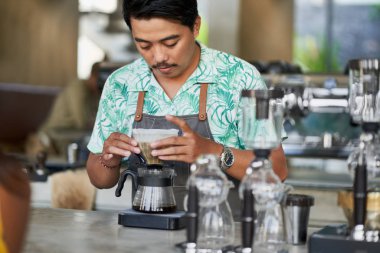 Gülümseyen etnik Endonezya barista ve küçük iş sahibi parlak trendy kahve dükkanı önlük giyen organik Fuar-Ticaret kahve hazırlanıyor Candid yaşam çekimi