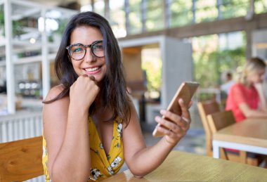 Modern trendy ve parlak kafe bitkiler ile cep telefonunda yazarak gülüyor İspanyol milenyal öğrenci Candid yaşam tarzı portre