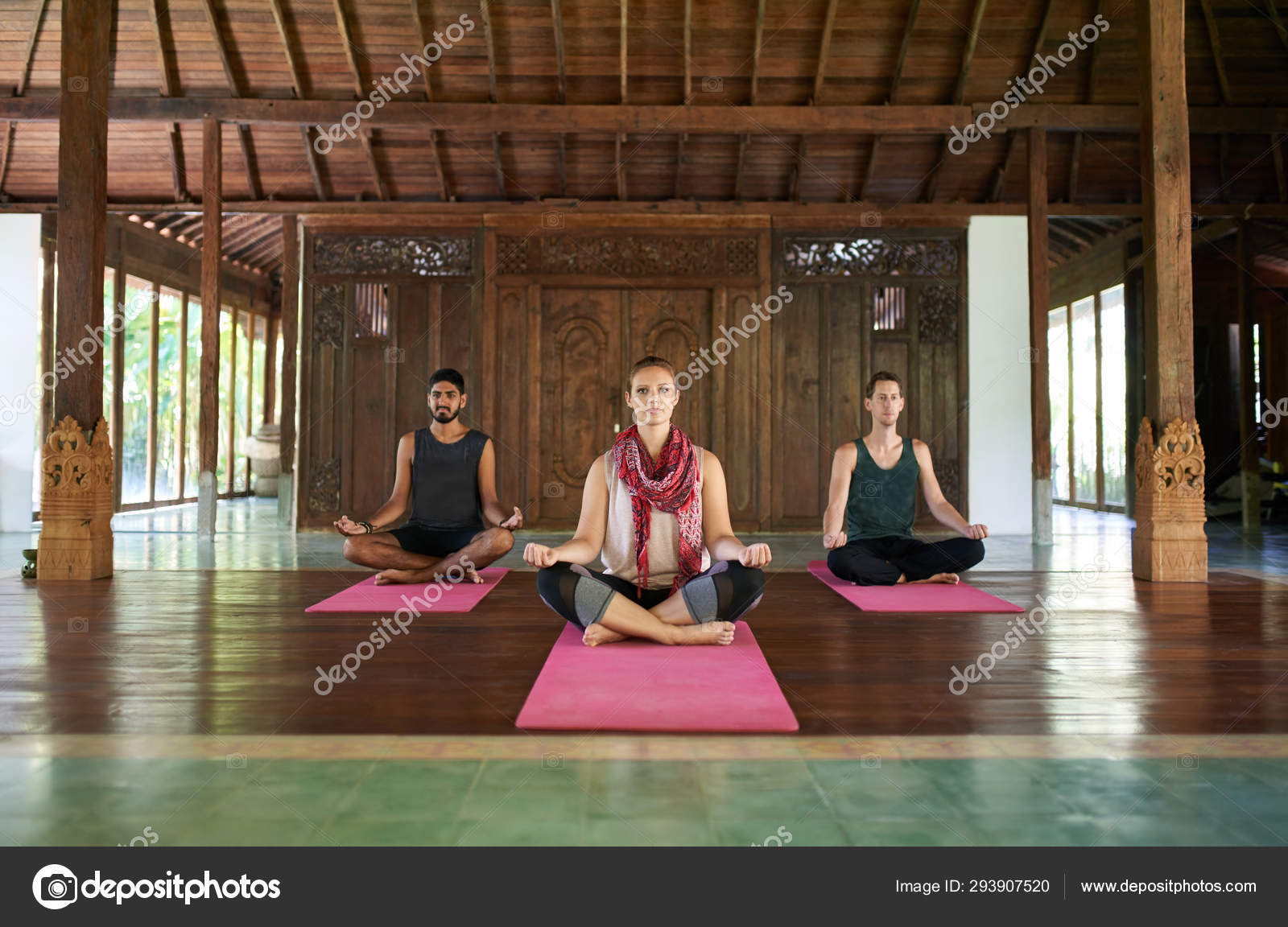 Três pessoas multi-étnicas sentadas em pose de lótus praticando ioga juntas  em um templo tradicional em Bali Indonésia fotos, imagens de © julief514  #293907520