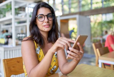 Bitkiler ile modern trendy ve parlak kafede cep telefonu yazarak İspanyol bin yıllık grafik tasarımcı gülen Samimi yaşam tarzı portresi