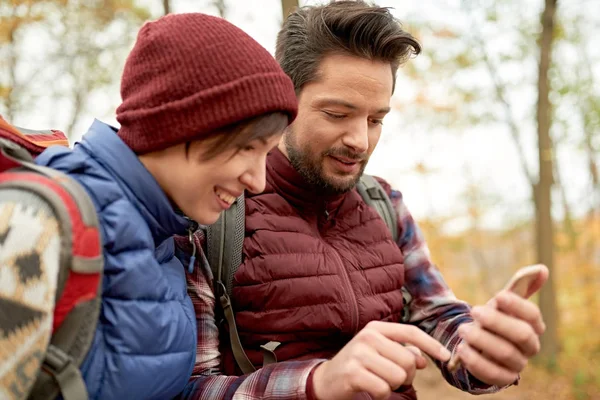 Un par de millennials canadienses tomando selfies con un smartphone en un bosque de otoño — Foto de Stock