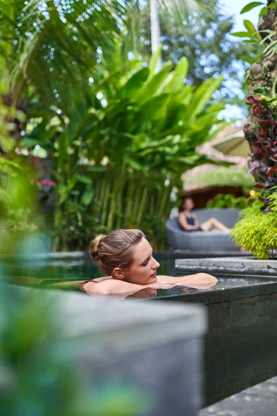 Досить мирна жінка розслабляє на відкритому повітрі в Сонячний і пишний камінь басейн розкішного готелю під час тропічного відпочинку на Балі — стокове фото