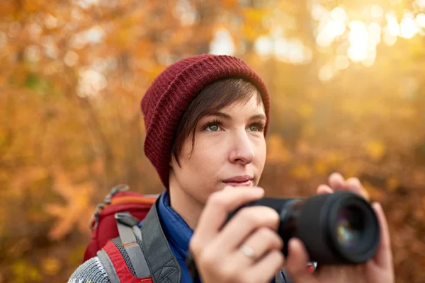 Atractiva chica caucásica tomando fotos con una cámara sin espejo a través del bosque en el otoño en Canadá — Foto de Stock