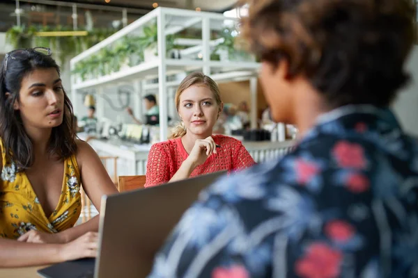 Candid grupo estilo de vida disparo de tres de moda mixta millennial compañeros de trabajo que se reúnen en el ordenador portátil en el restaurante hipster brillante — Foto de Stock