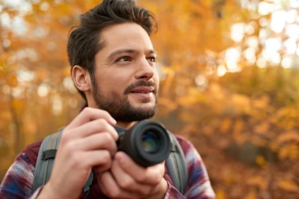 Atractivo hombre caucásico tomando fotos con una cámara sin espejo a través del bosque en el otoño en Canadá — Foto de Stock