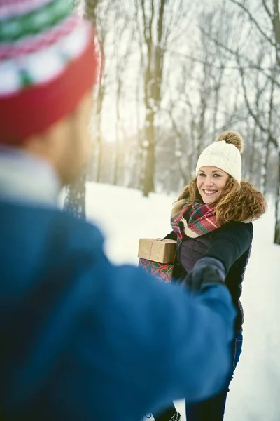 POV image of a diverse couple holding Christmas presents while walking through a winter forest — Stock Photo, Image