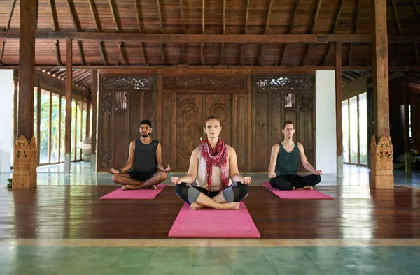 Trois personnes multi-ethniques assis dans la pose de lotus pratiquant le yoga ensemble dans un temple traditionnel à Bali Indonésie — Photo