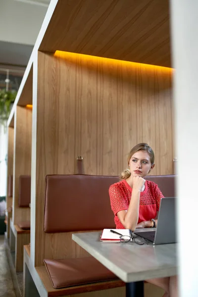 Estilo de vida close-up retrato de beaufitul focado loira caucasiana millennial freelancer trabalhando em grande mesa de madeira de um moderno café da moda — Fotografia de Stock