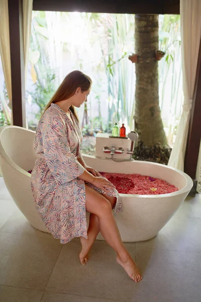 Mulher milenar bonita sendo mimada no resort tropical e spa com banho de ervas sereno e terapia de flores em Bali — Fotografia de Stock