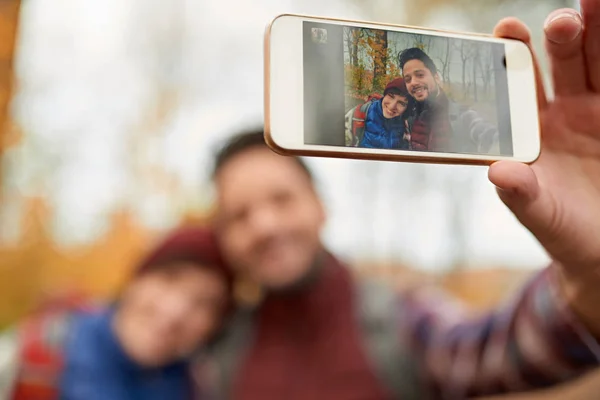Casal de millennials canadenses tirando selfies com um smartphone em uma queda forrest — Fotografia de Stock