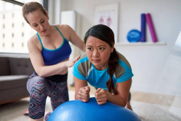 Fisioterapeuta mujer caucásica dando una sesión de entrenamiento a una paciente china de mediana edad en una pelota de estabilidad —  Fotos de Stock