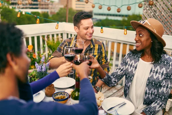 Group of diverse friends having dinner and a glass of wine al fresco in urban setting — Stock Photo, Image