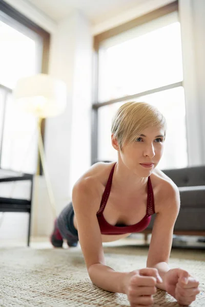 Trendfrau macht Brettübungen im Rahmen ihrer Fitness-Morgenroutine — Stockfoto