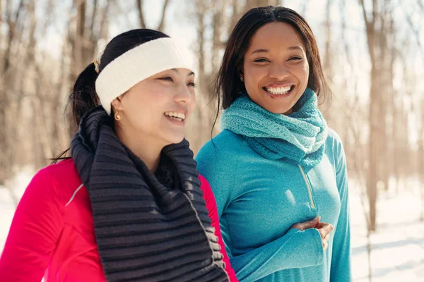 Multietniska par kvinnliga vänner att ta en paus från jogging i snön på vintern — Stockfoto