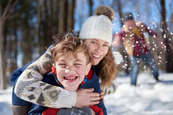Familia feliz con hijo disfrutando jugando en nieve fresca durante el invierno y teniendo una pelea de bolas de nieve — Foto de Stock