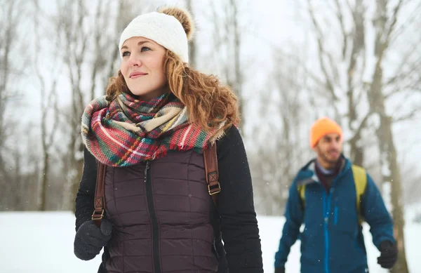 Pareja diversa sonriente explorando la naturaleza en Canadá mientras camina a través de un bosque de invierno — Foto de Stock