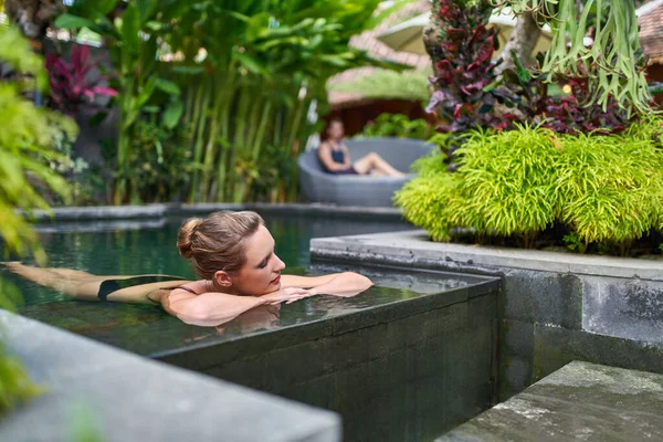 Прекрасна спокійна жінка відпочиває надворі в сонячному і пишному кам "яному басейні розкішного готелю під час тропічних проходів на Балі. — стокове фото