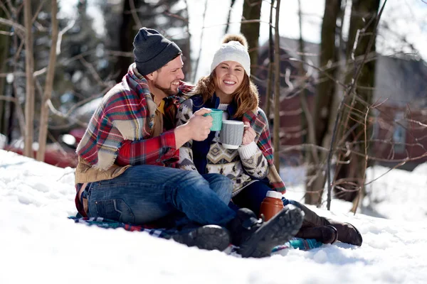 Couple in love enjoying a tender moment in fresh snow during wintertime and drinking hot chocolate together — Stock Photo, Image