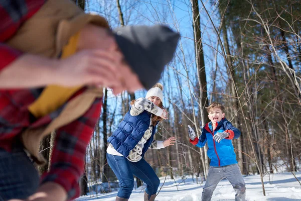 Familia feliz con hijo disfrutando jugando en nieve fresca durante el invierno y teniendo una pelea de bolas de nieve — Foto de Stock