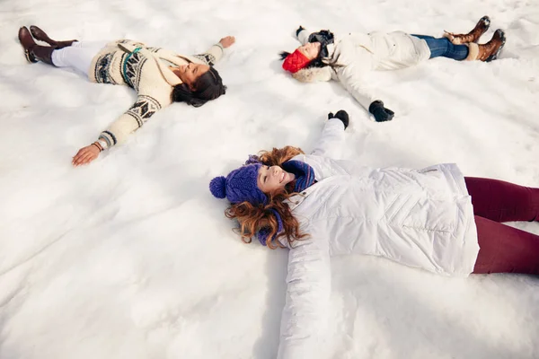 Grupo de amigas haciendo ángeles de nieve en invierno —  Fotos de Stock