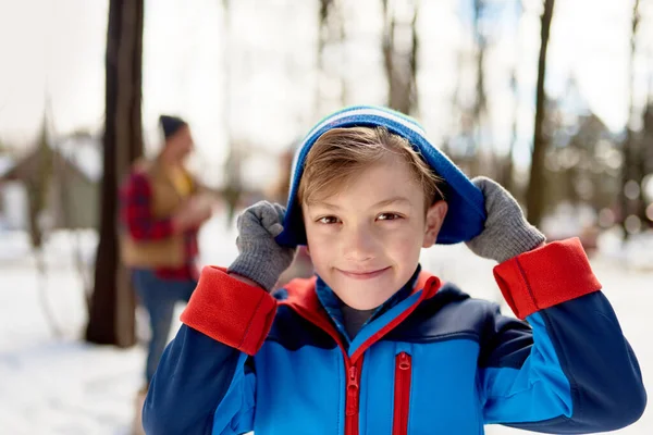 Retrato de un niño y su familia disfrutando jugando en nieve fresca durante el invierno y usando un sombrero de punto — Foto de Stock