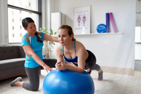 Chinesische Personal Trainerin während einer Trainingseinheit mit einer attraktiven blonden Kundin in einer hellen Arztpraxis — Stockfoto