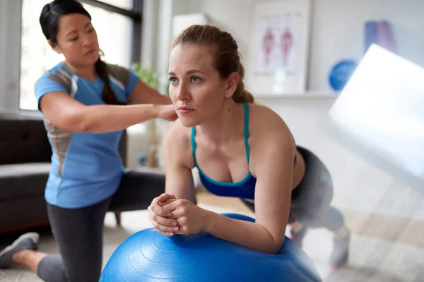 Chinesische Personal Trainerin während einer Trainingseinheit mit einer attraktiven blonden Kundin in einer hellen Arztpraxis — Stockfoto