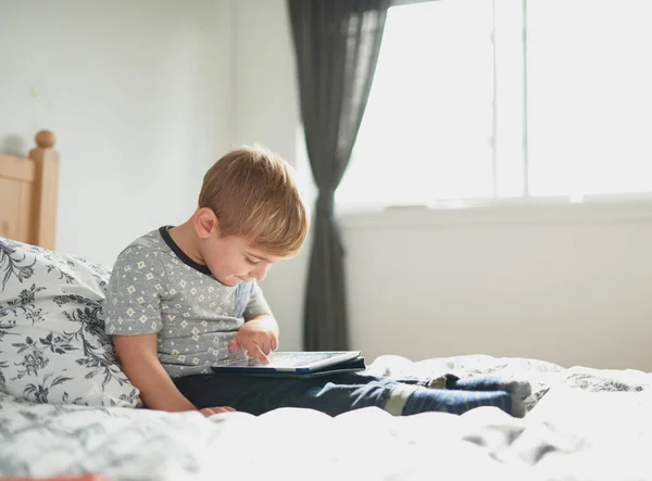 Незалежна маленька дитина вчиться читати вдома через технол — стокове фото