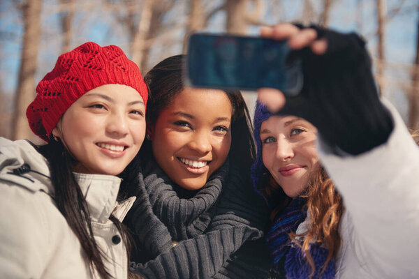 Group of girl friends enjoying taking selfies in the snow in winter