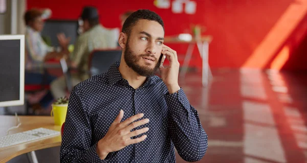 Designer masculino confiante falando em um telefone celular em vermelho creativ — Fotografia de Stock