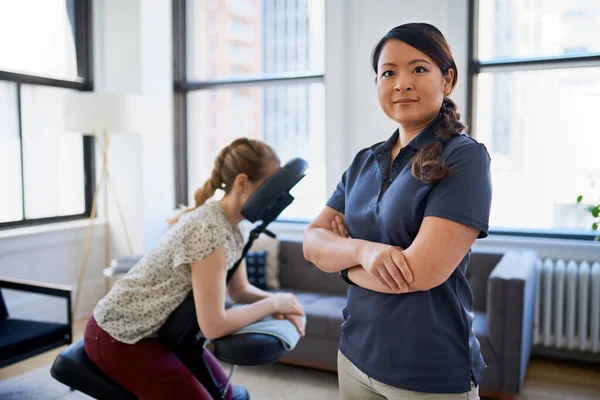 Portrait of a Chinese woman massage therapist giving a neck and back pressure treatment to an attractive blond client at her workplace in a bright office — Stock Photo, Image
