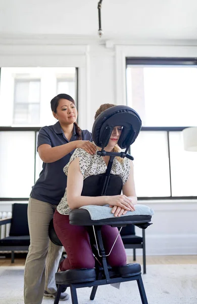 Chinese woman massage therapist giving a neck and back pressure