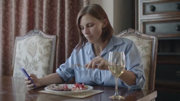 갈색 머리 여자 데 식사 와 유리 의 화이트 와인 이야기 로 전화 — 비디오