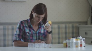 Genç kadın sıralama ve provence iç masada oturan vitamin alarak. Kadınlar onun sağlığıyla ilgilenir.