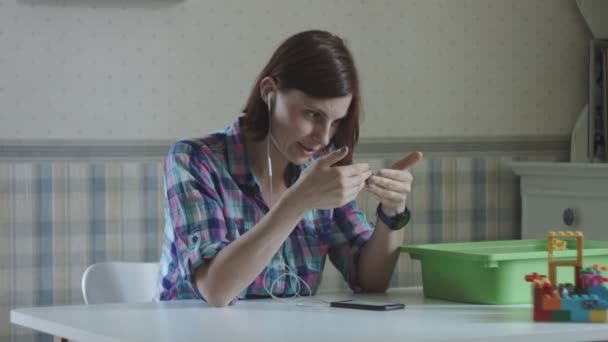 Cansado joven madre trabajadora hablando por teléfono en provence interior sentado en la mesa con juguetes — Vídeo de stock