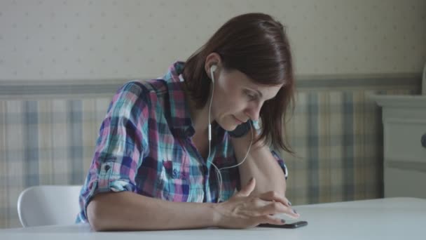 年轻的女性自由职业者打字在电话在耳机在证明内部 — 图库视频影像