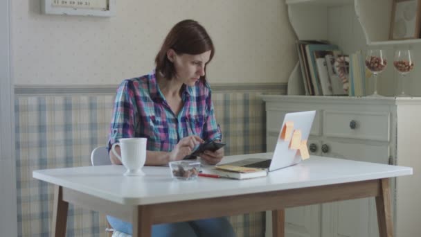 自宅で働く若い女性フリーランス。プロヴァンスのインテリアでテーブルに座ってオンラインで話すブルネットの女性. — ストック動画